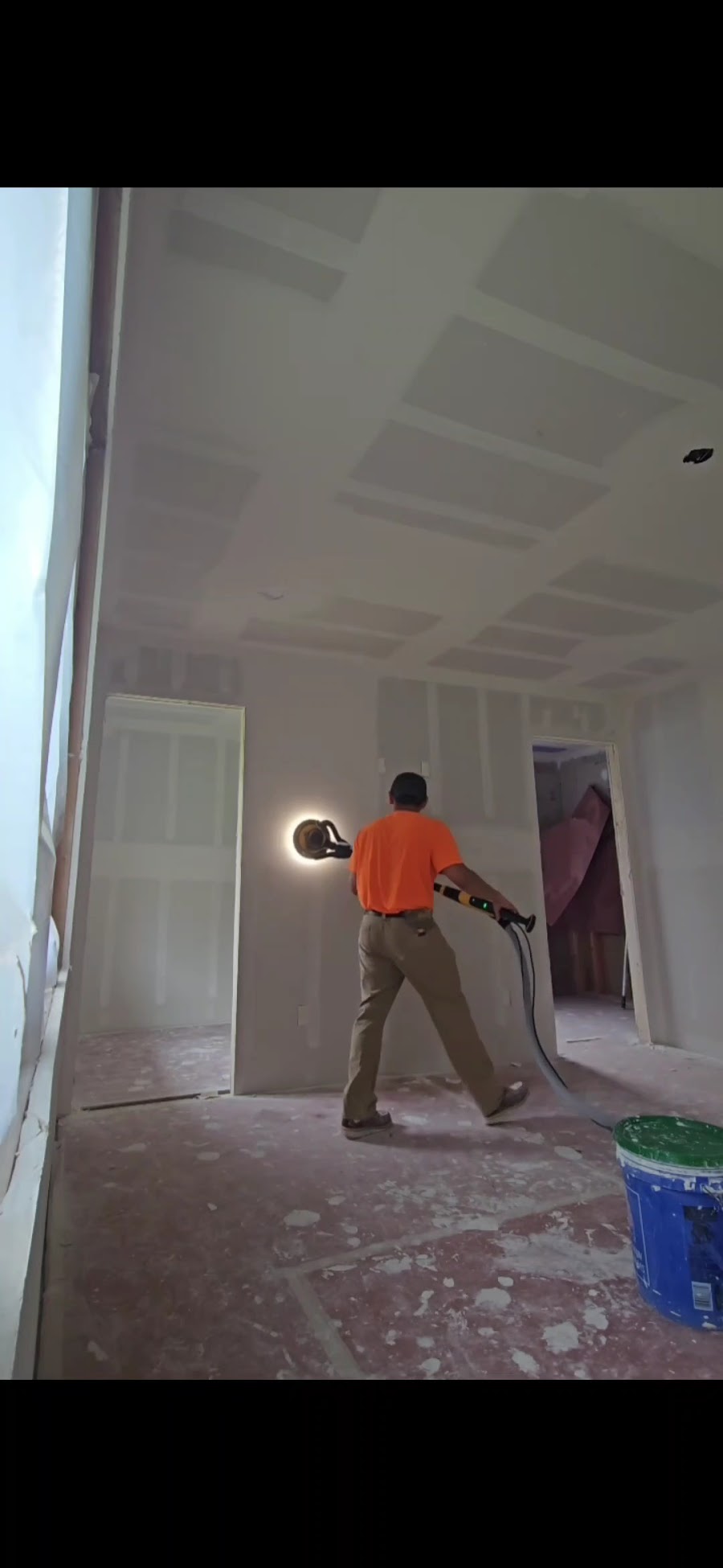 Joel sanding a finished drywall wall on a job site